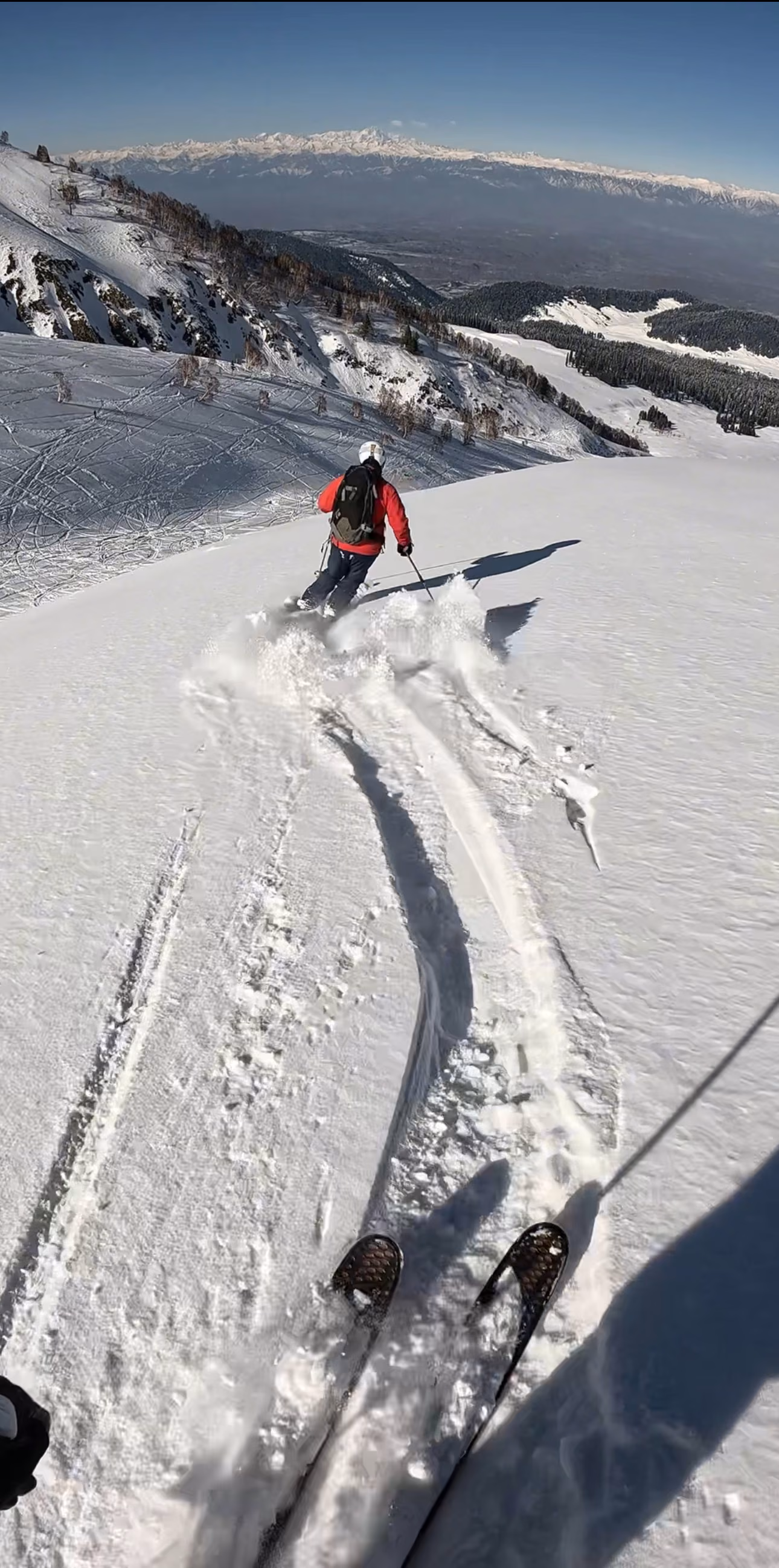 Skier in an orange jacket on a ridge above Gulmarg