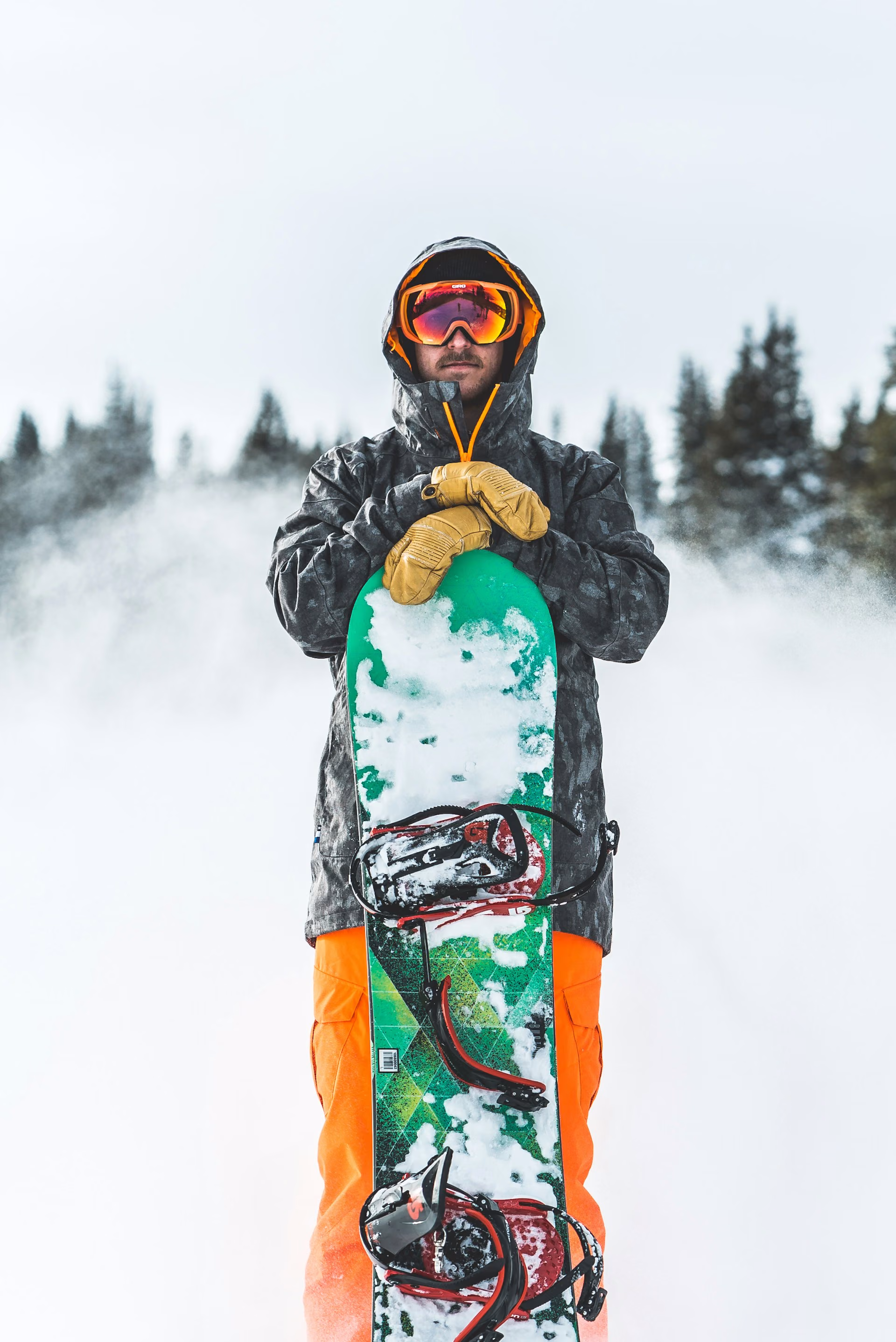 Snowboarder standing with a board on a snow covered slope