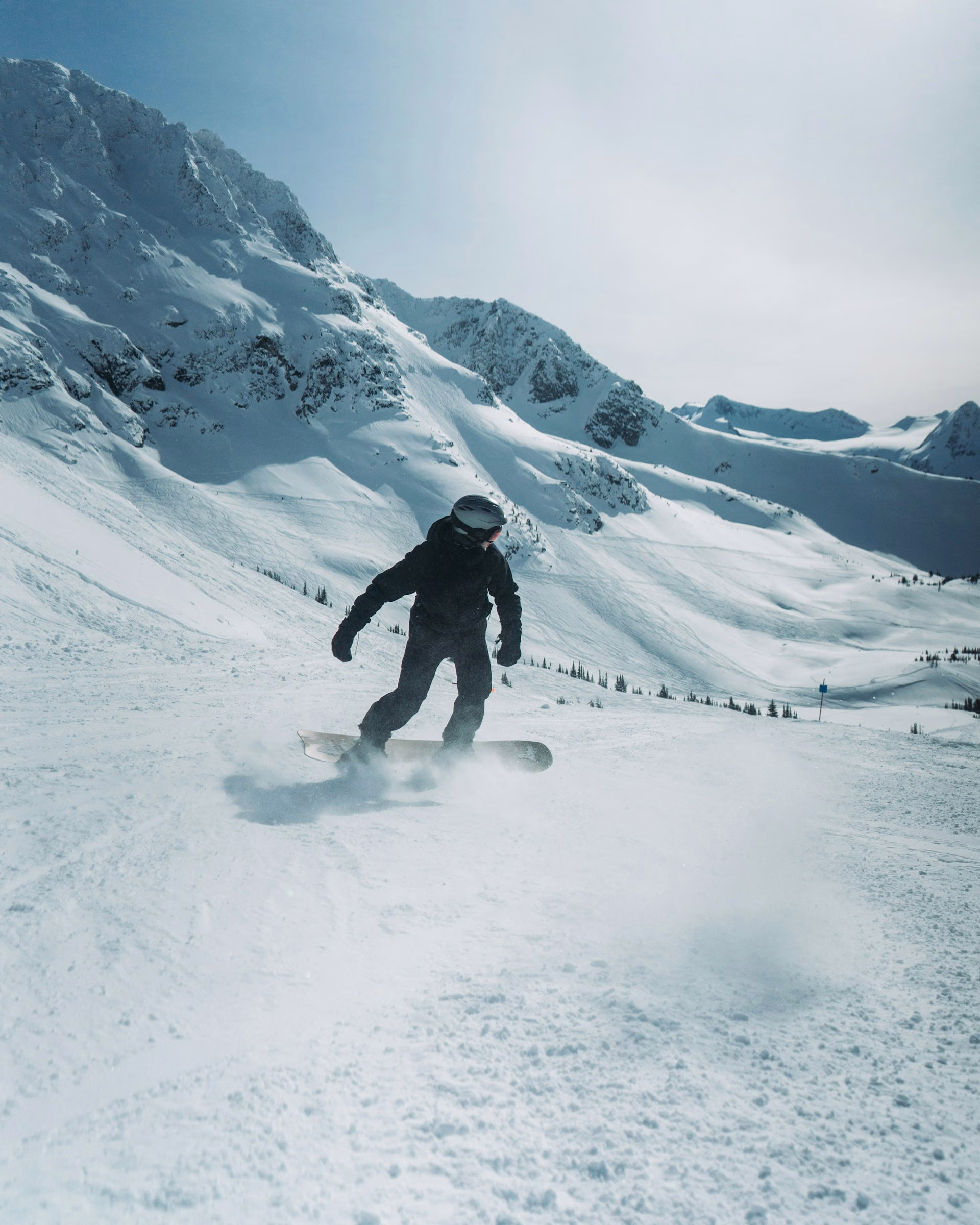 Snowboarder riding an open slope below rocky peaks