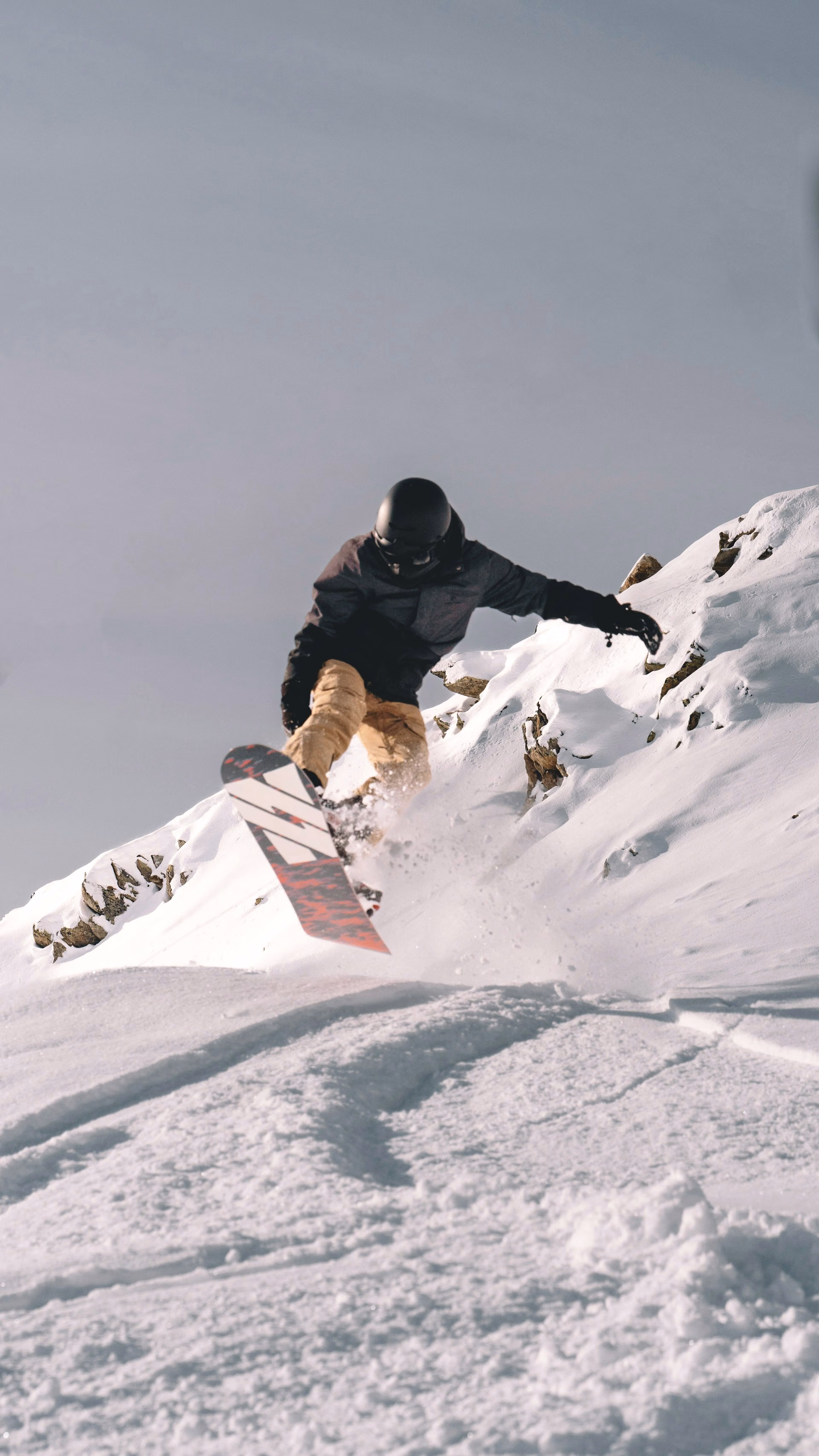 Snowboarder carving along a steep snow covered ridge