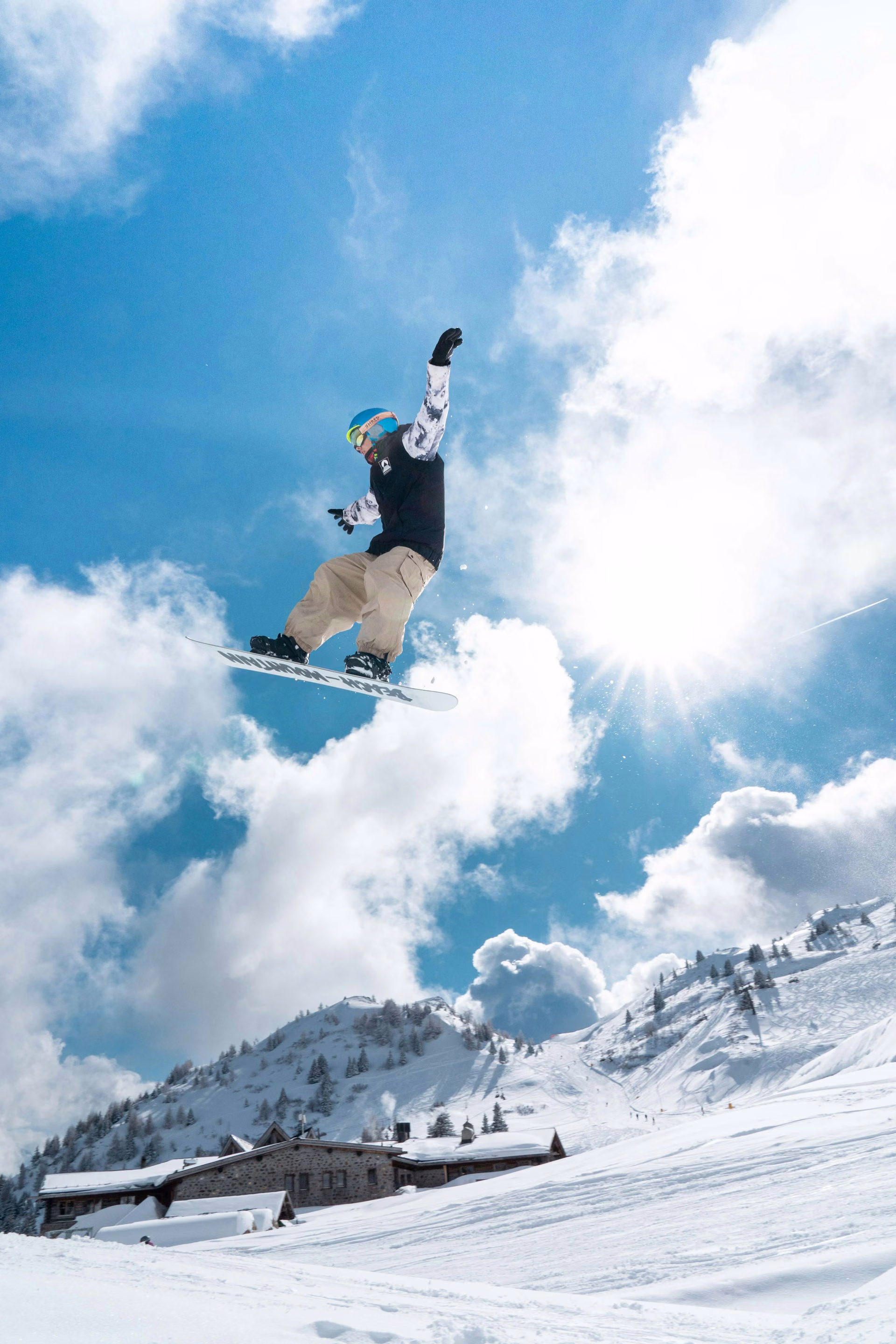 Snowboarder airborne off a jump against a bright sky